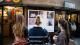 The backs of three people's heads as they view student artwork in the Earth Day exhibition.